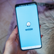 A photo of a person holding a phone with the Waze logo